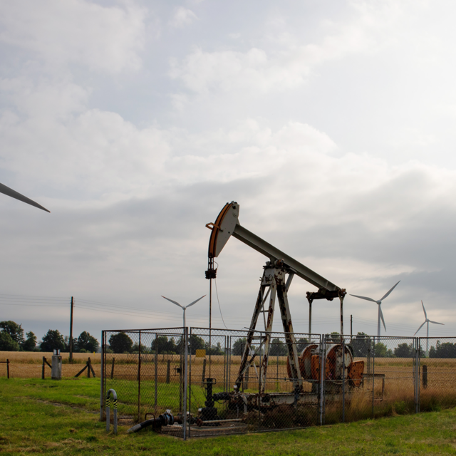Photo shows energy windmills and an oil pumpjack near each other in a landscape